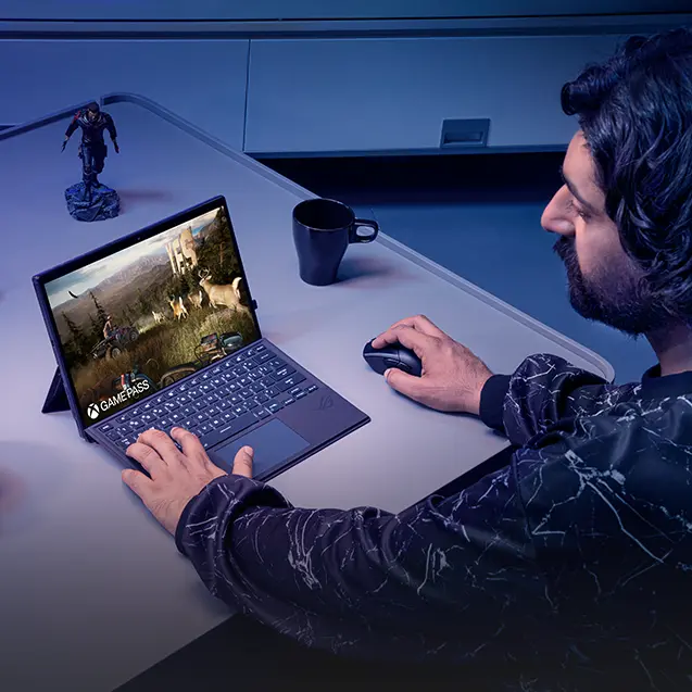 A man playing video games on the Flow Z13 with attached keyboard and mouse.
