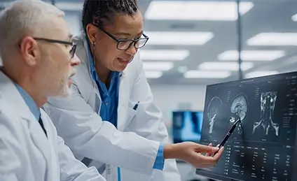 Two researchers are discussing a medical image on a screen.