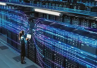 A woman holds a laptop in a data center aisle with rows of server racks and blue network light trails