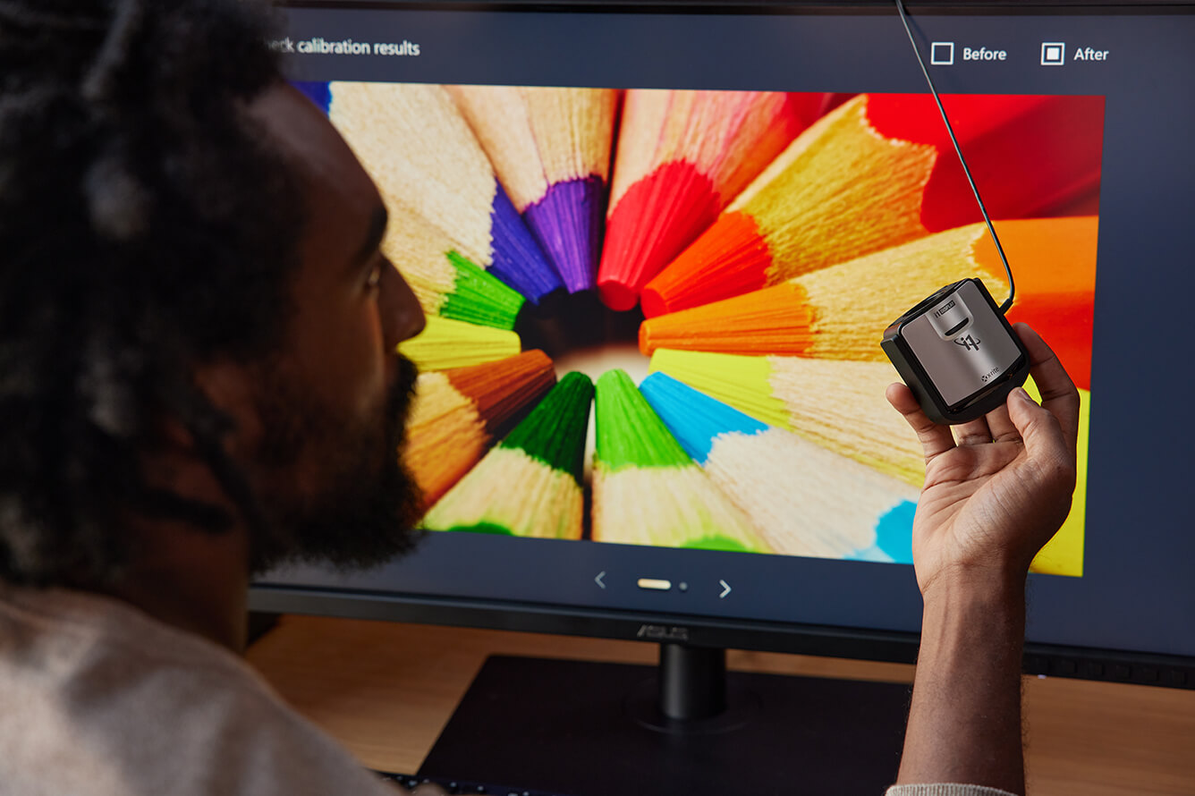 A man holding a calibrator in front of ProArt Display