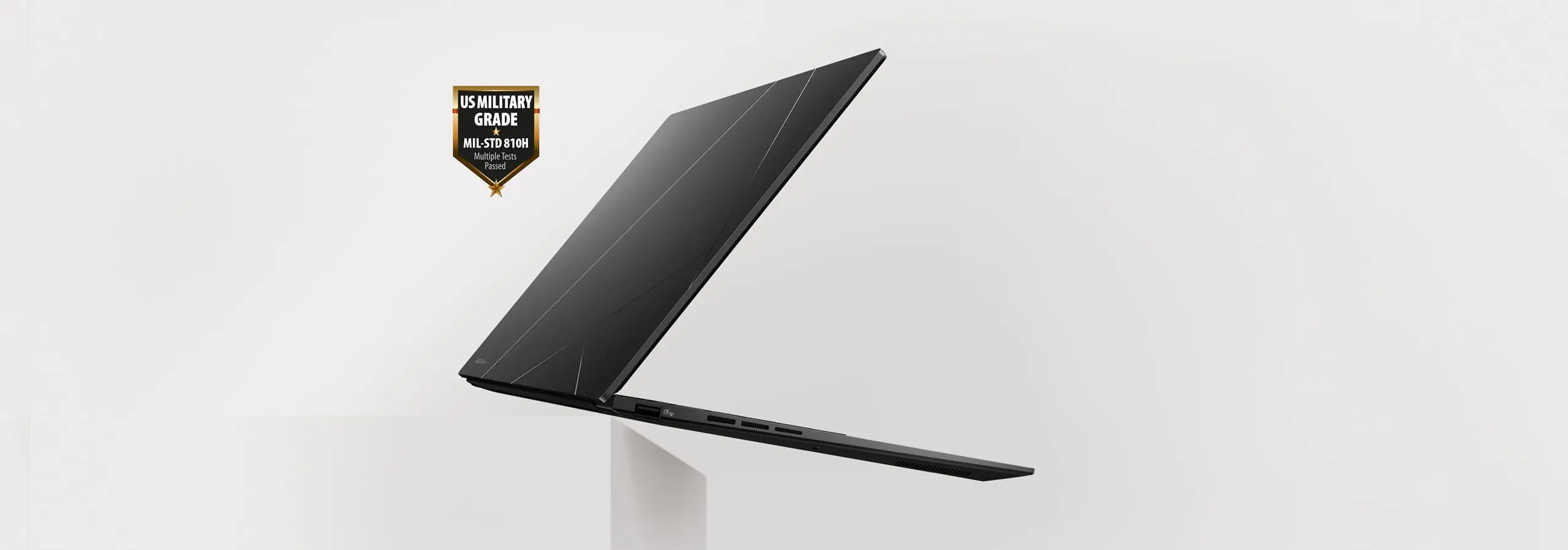 Zenbook 14 OLED laptop is floating in mid-air with US military garde icon next to it.